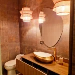 Mueble de baño contemporáneo con mesón en piedra sintetizada, veta tipo madera y espejo orgánico en Medellín